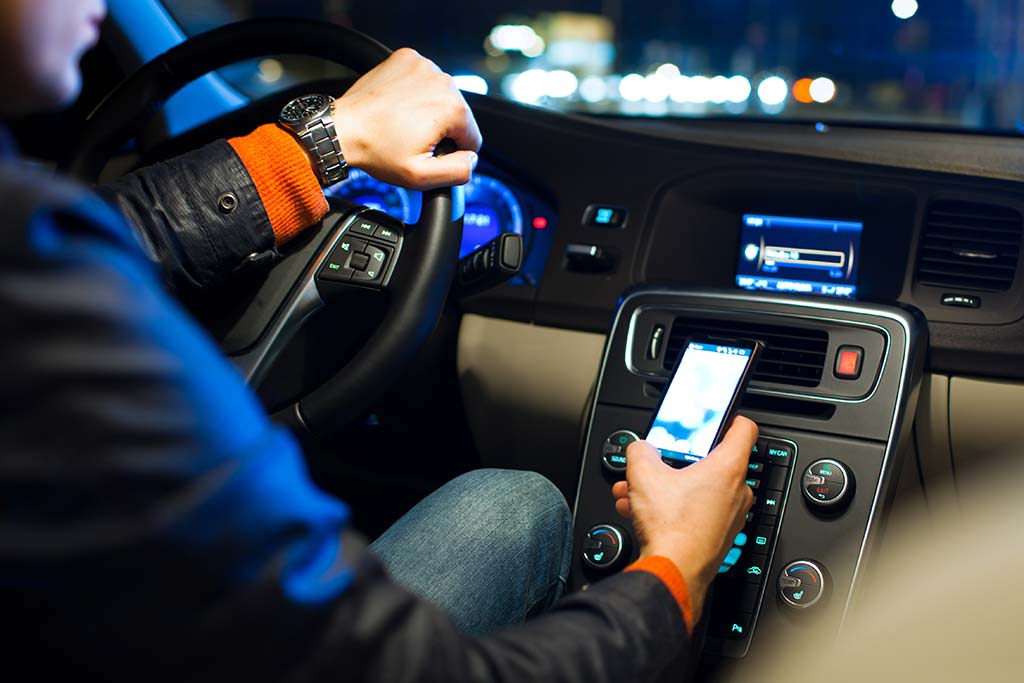 Un uomo mentre sceglie dove nascondere il cellulare spia in macchina