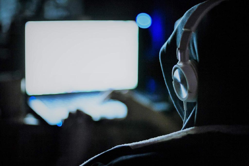 Uno spione ascolta conversazioni a distanza con le cuffie davanti al PC