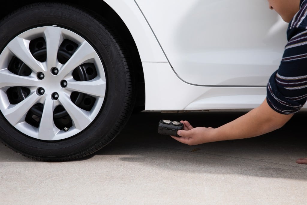 Un uomo installa un localizzatore GPS sull'auto della moglie