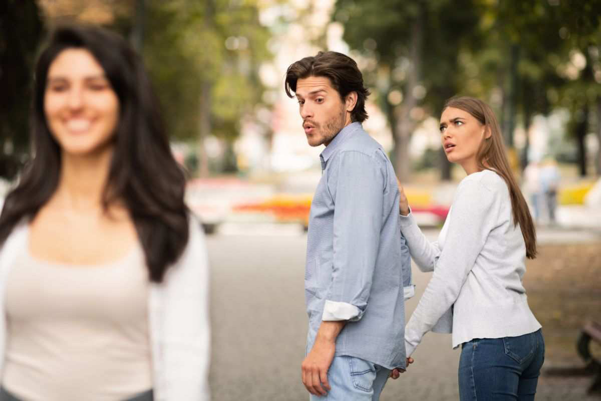 Un uomo guarda un'altra donna mentre è con la compagna: questo è uno dei più tipici segnali di tradimento