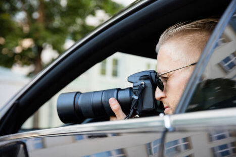 Un investigatore privato scatta una fotografia appostato nella sua auto