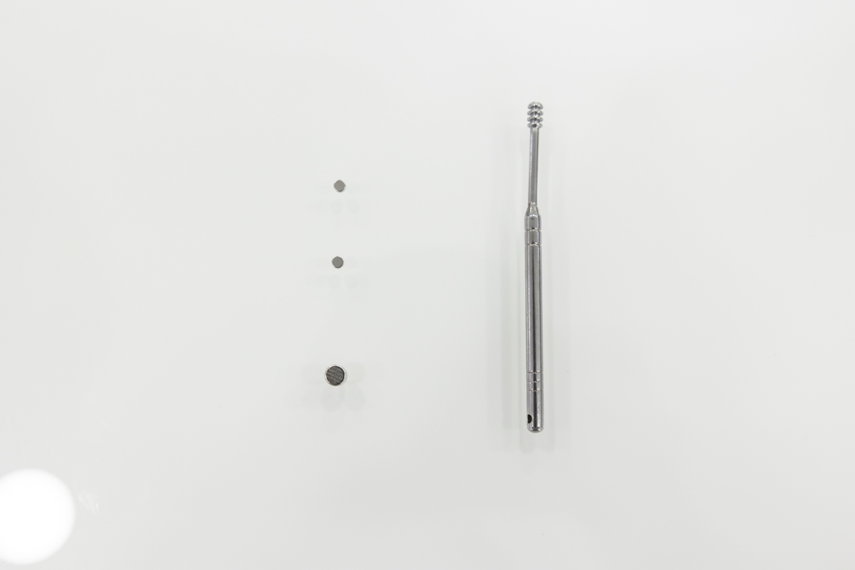 Kit composto da due auricolari nanocalamitati con estrattore metallico e calamita per la rimozione degli auricolari dall'orecchio AURIC.09